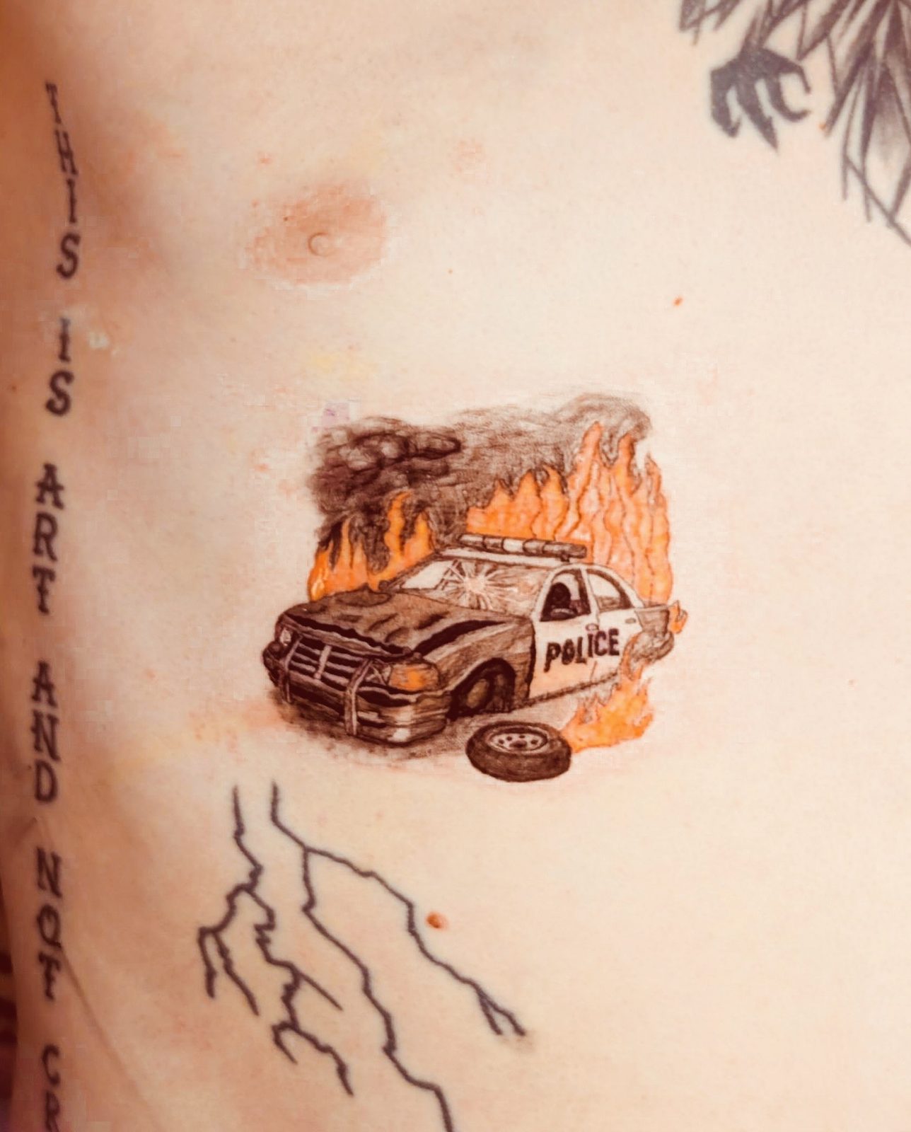 Color tattoo of a burning police car on torso